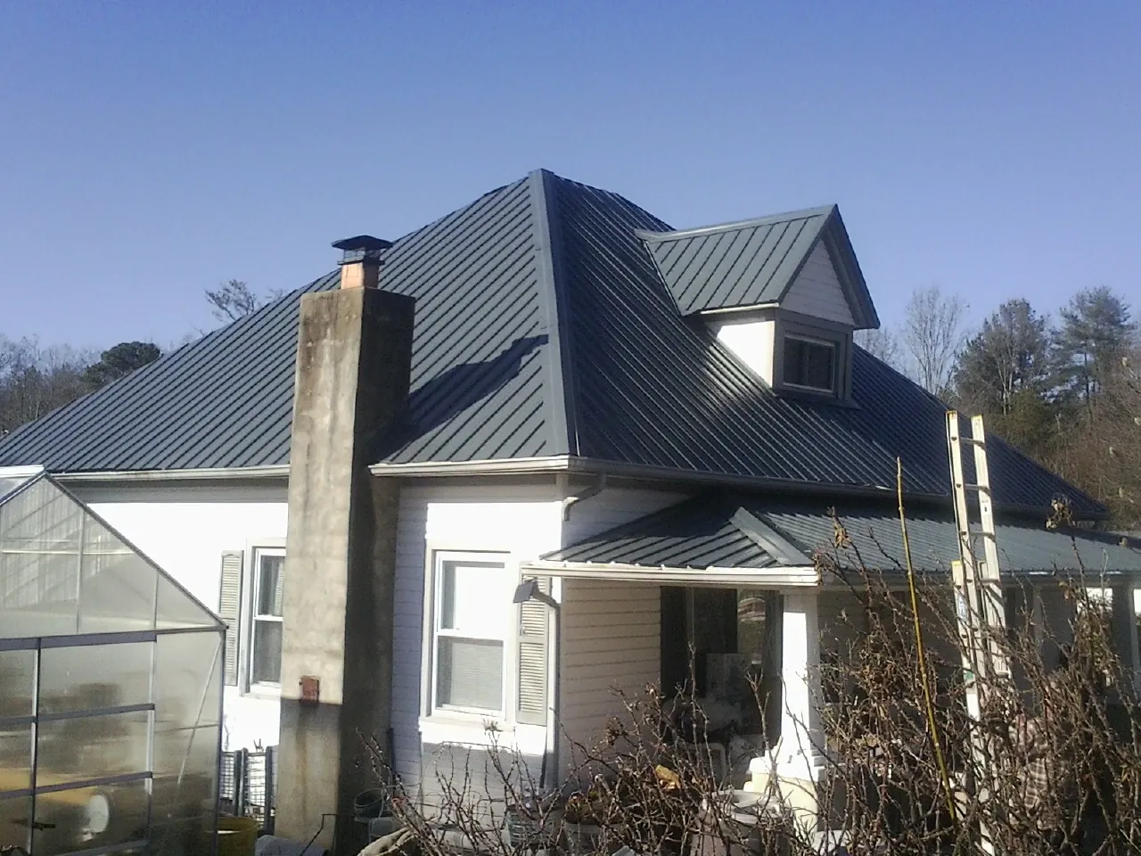 Dark blue standing seam metal roof on a white farmhouse with dormer — Slate & Tile Roof Repair by Roofing Brothers in Burley