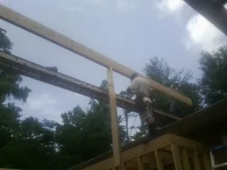 Carpenter setting a ridge beam over a new addition frame — Ice Dam Removal by Roofing Brothers in Burley