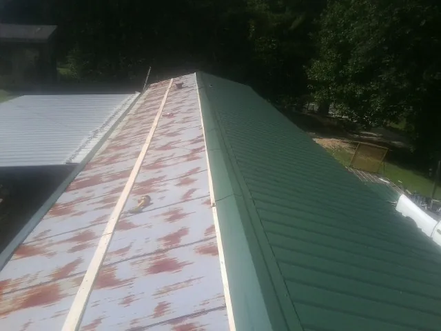 Old rusted panels beside newly installed green metal roofing — Wind Damage Roof Repair by Roofing Brothers in Burley