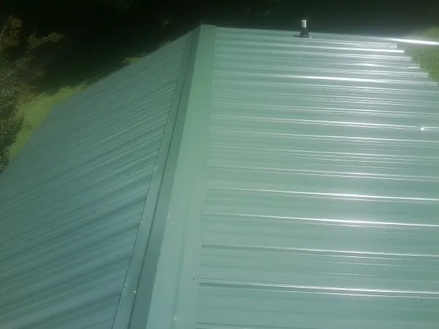 New green metal panels meeting at the ridge of a roof — Flat Roof Repair work by our crew in Burley