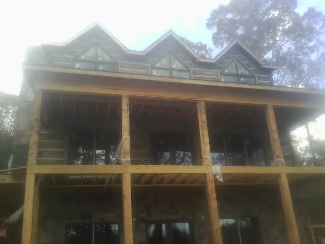 Dormers and porch framing on a large log home under construction — Roof Coating work by our crew in Burley