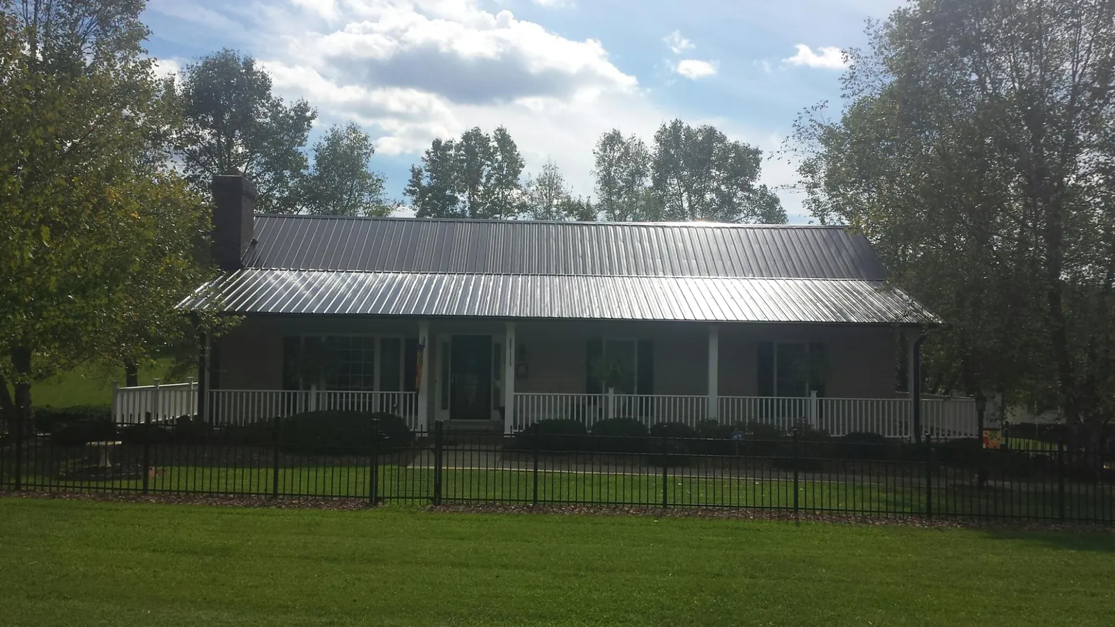Gray metal roof on a brick ranch with a full width front porch — Gutter Guard Installation work by our crew in Burley