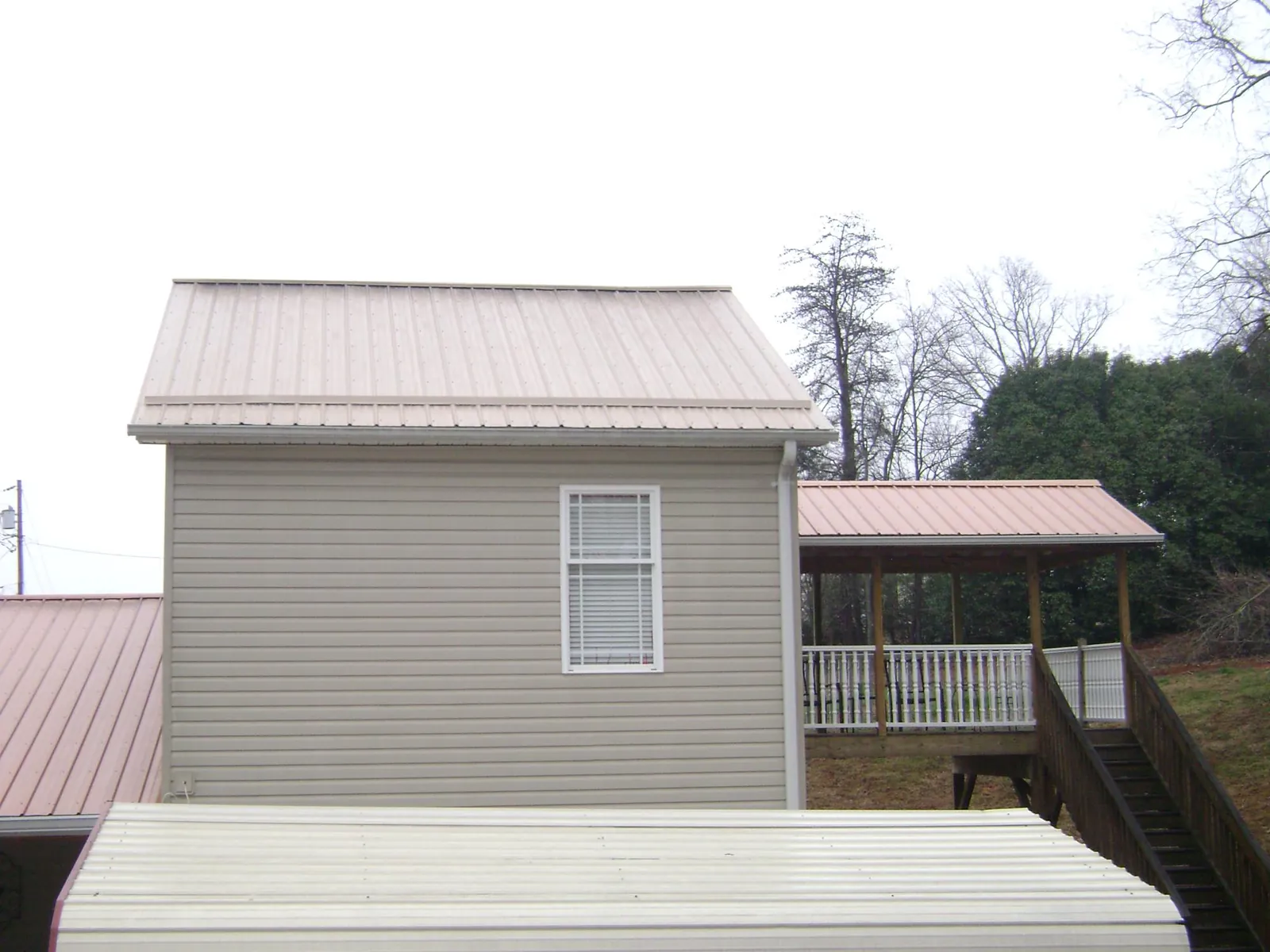 Tan metal roofs on a two story addition and attached porch, from a Roof Replacement job in Burley