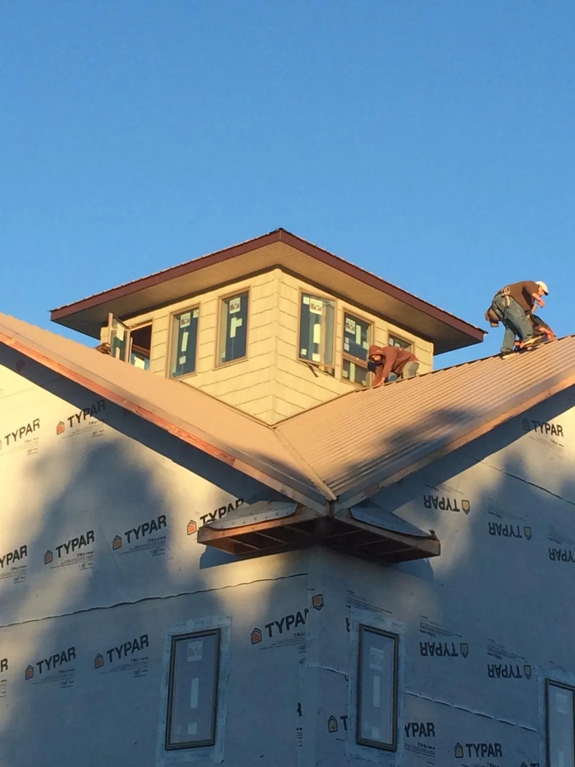 Roofers working around a rooftop cupola on a new metal roof at sunset — Roof Waterproofing in Burley by Roofing Brothers